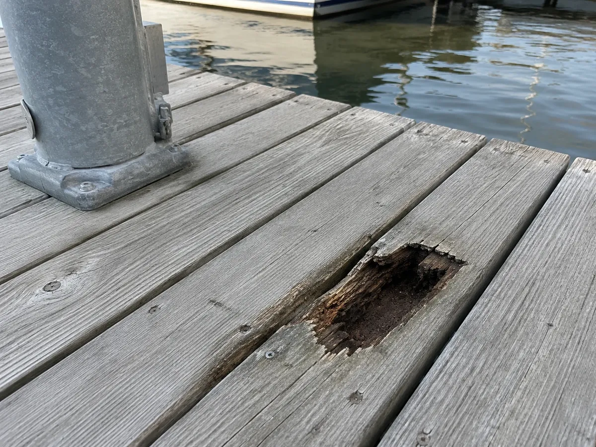 Photo of a dock board rotted through, leaving a hole in the decking